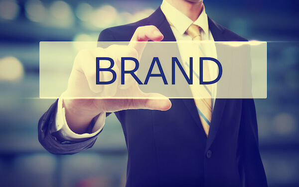 Business man holding Brand on blurred abstract background